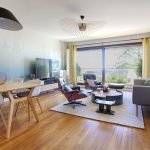 lampe arc noire, table chêne, fauteuils table blancs, parquet chêne style scandinave , meuble tv, rideaux jaune oeillets, vertigo